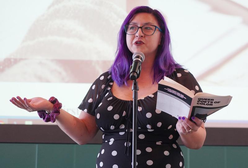 woman talking on stage with a book