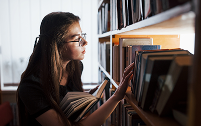 Female student is in library that is full of books