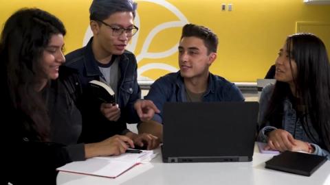 Four students sitting in front of a laptop