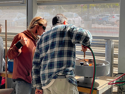 Instructor guiding a student working on the centrifugal casting machine